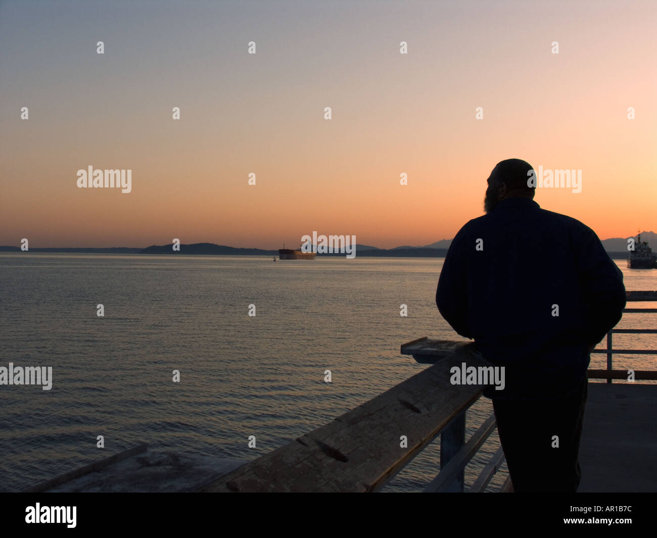 L'uomo pubblico sulla pesca del molo a guardare il tramonto su Seattle Waterfront a Myrtle Edwards Park Seattle Washington Foto Stock