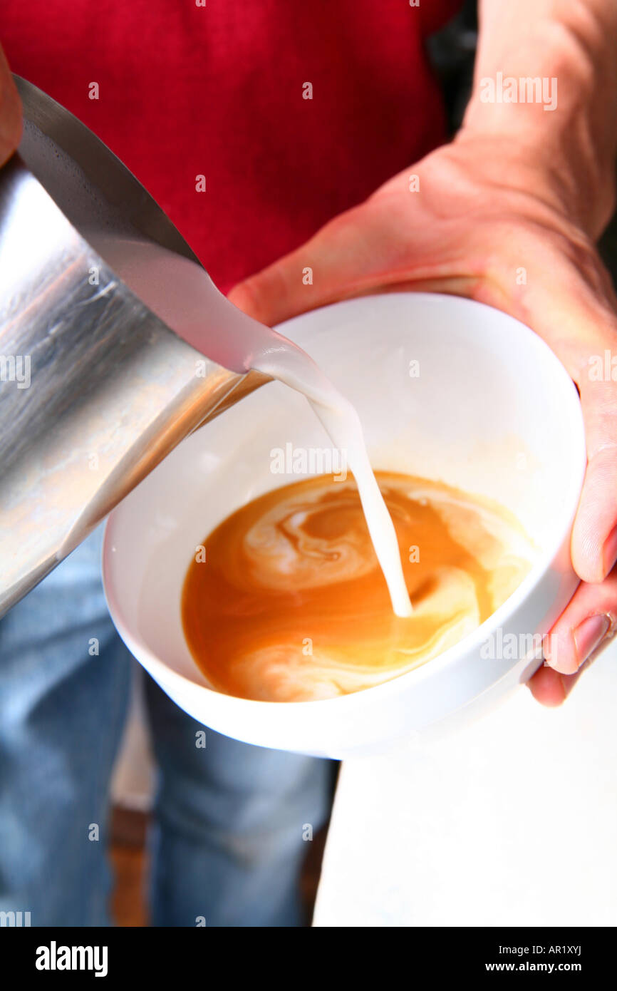 Un barista versando latte vaporizzato in un caffè Foto Stock