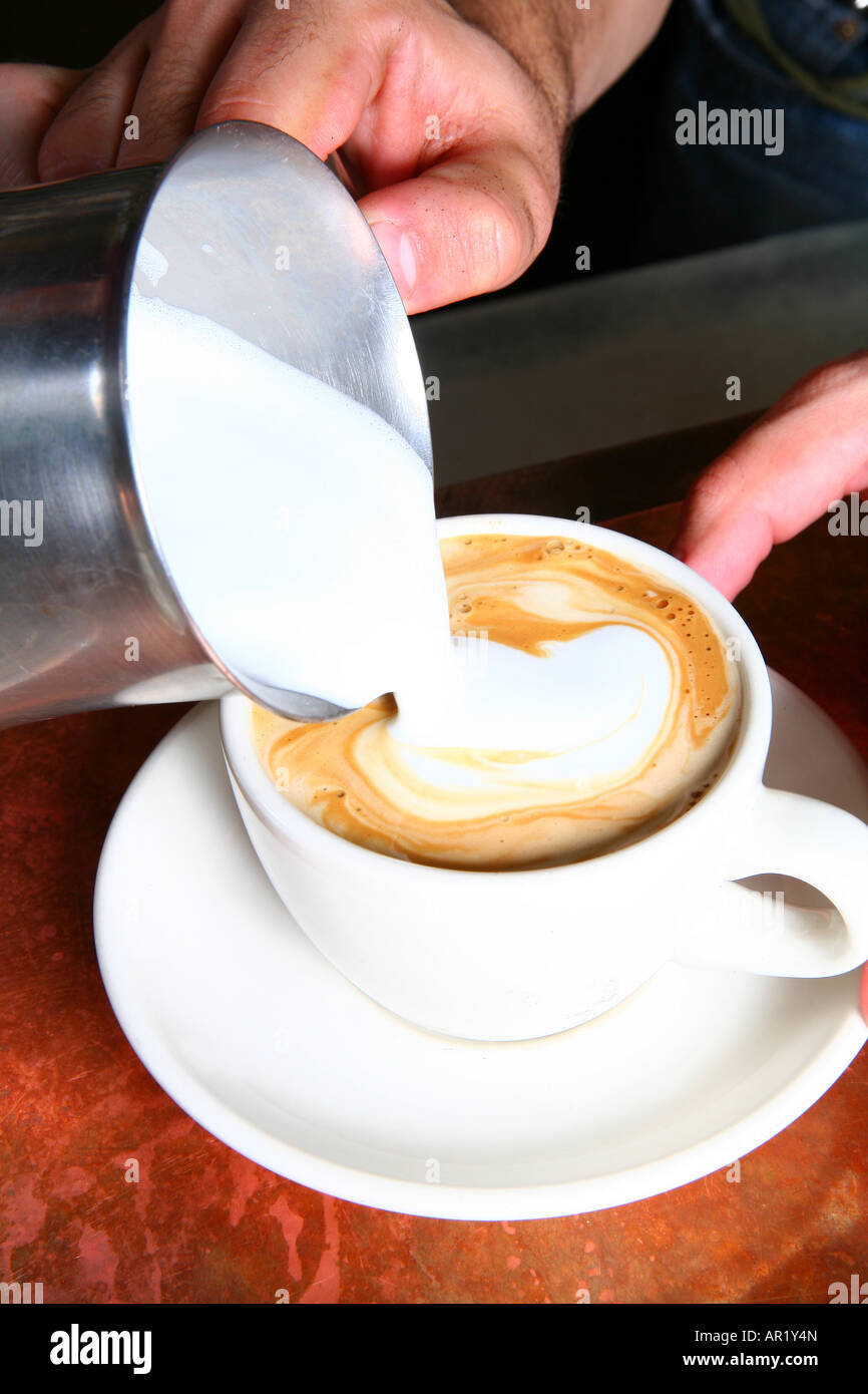 Un barista rendendo un latte Foto Stock