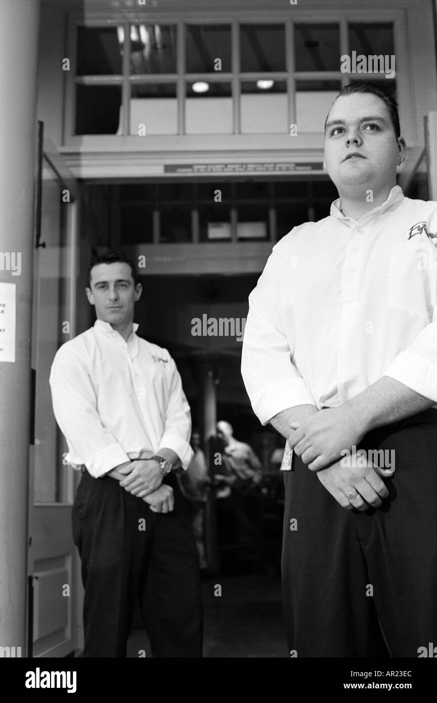 Due maschio portieri buttafuori al di fuori di un pub in bianco e nero monocromatico ingresso ritratto ritratti portieri portiere buttafuori buttafuori Foto Stock