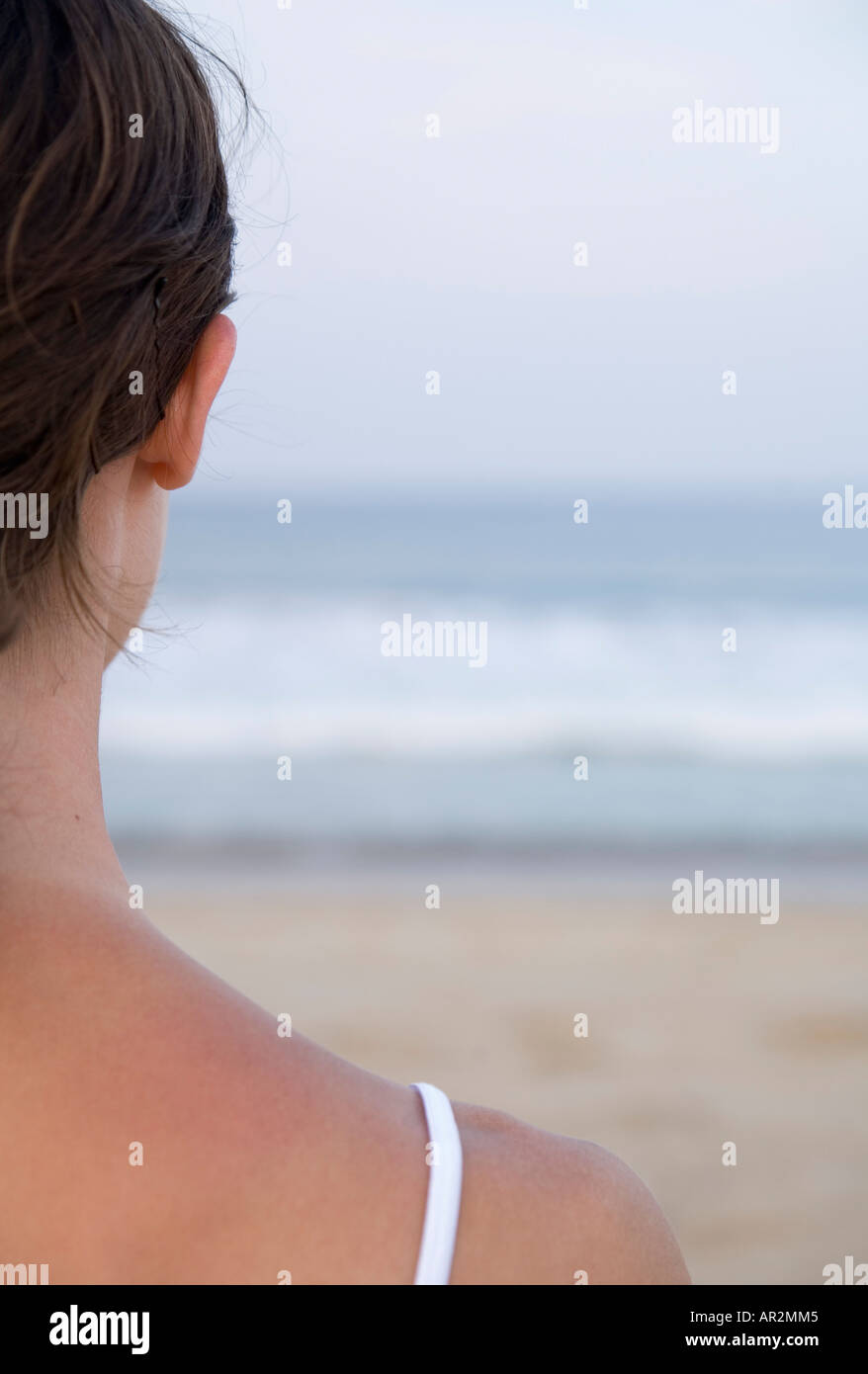 Donna sulla spiaggia affacciata sul mare Foto Stock