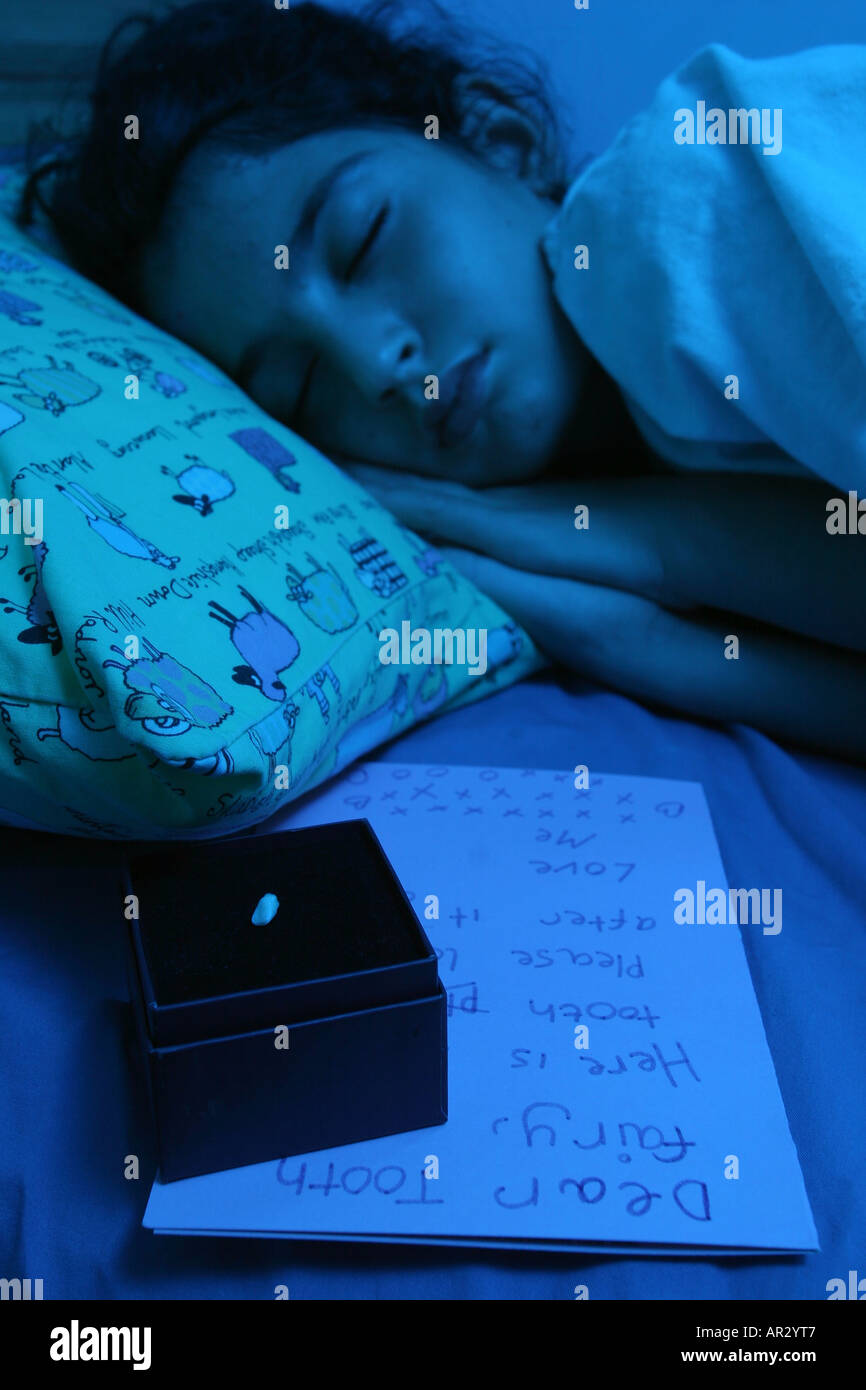 Una giovane ragazza nel suo letto con una nota per il dente di fata accanto al suo unico dente di latte. Foto Stock
