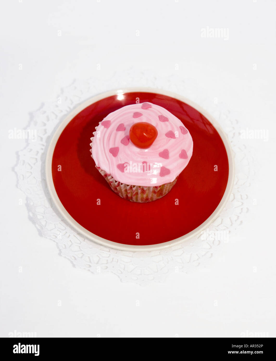 Home coppa cotta dolci (o torta di fata) - torte a base di pan di Spagna con Rosa ghiaccio fondente servita su una Cina rossa piastra. Foto Stock