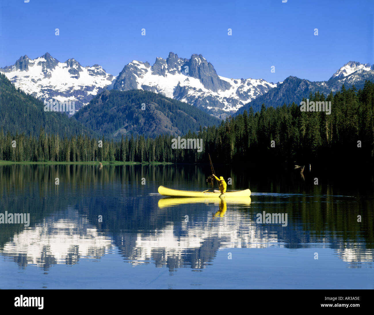 Cooper lago nel centro di Washington Cascade Mountains con un pescatore in una canoa gialla sulle placide acque del lago Foto Stock