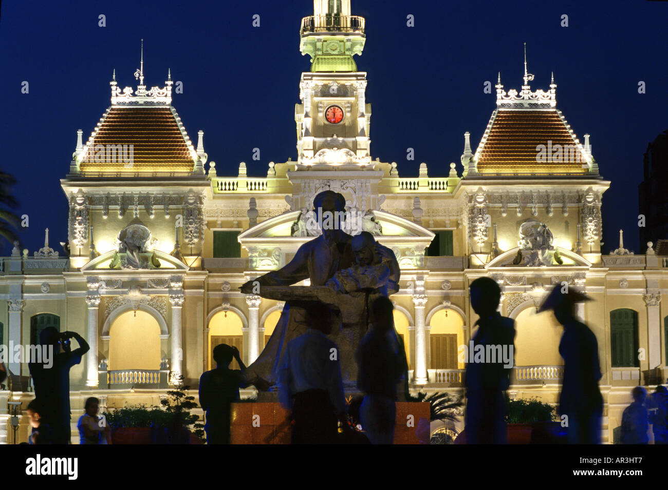 Statua e le persone di fronte alla città illuminata hall di notte, Ho Chi Minh City, Vietnam Asia Foto Stock