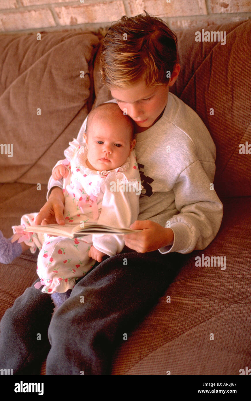 Il fratello di 7 anni la lettura di prenotare per 3 mesi la sorella del bambino a casa. Burnsville Minnesota USA Foto Stock