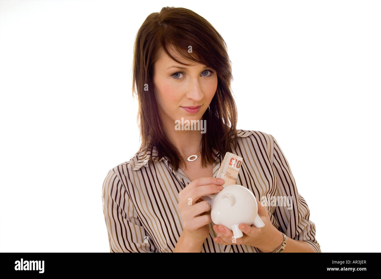 Donna mettendo a dieci pound nota in un piggybank Foto Stock