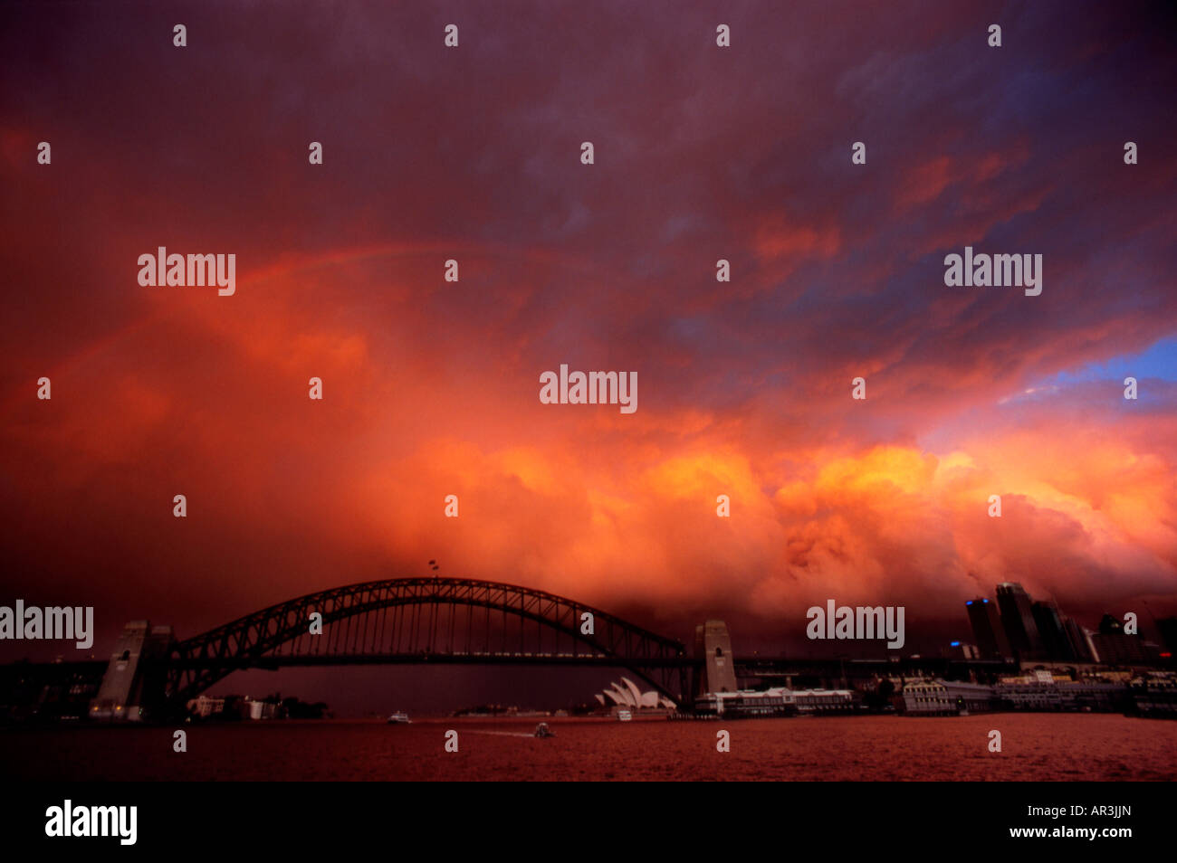 Tempesta su Sydney Harbour, illuminata in modo spettacolare tramonto da McMahon punto, Opera House di Sydney e il Sydney Harbour Bridge distanza Foto Stock