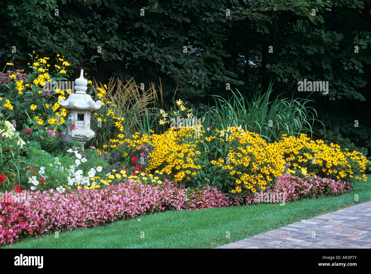 Giardino di confine di annuari e piante perenni lungo il vialetto di MINNESOTA HOME INCLUDE CONEFLOWERS, BEGONIE, erbe e DAYLILIES. Foto Stock