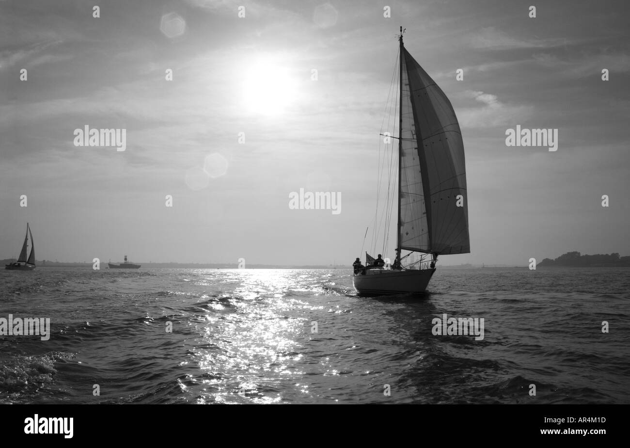 Immagine in bianco e nero alla ricerca attraverso il mare con una barca a vela in immagine e più barche a distanza Foto Stock