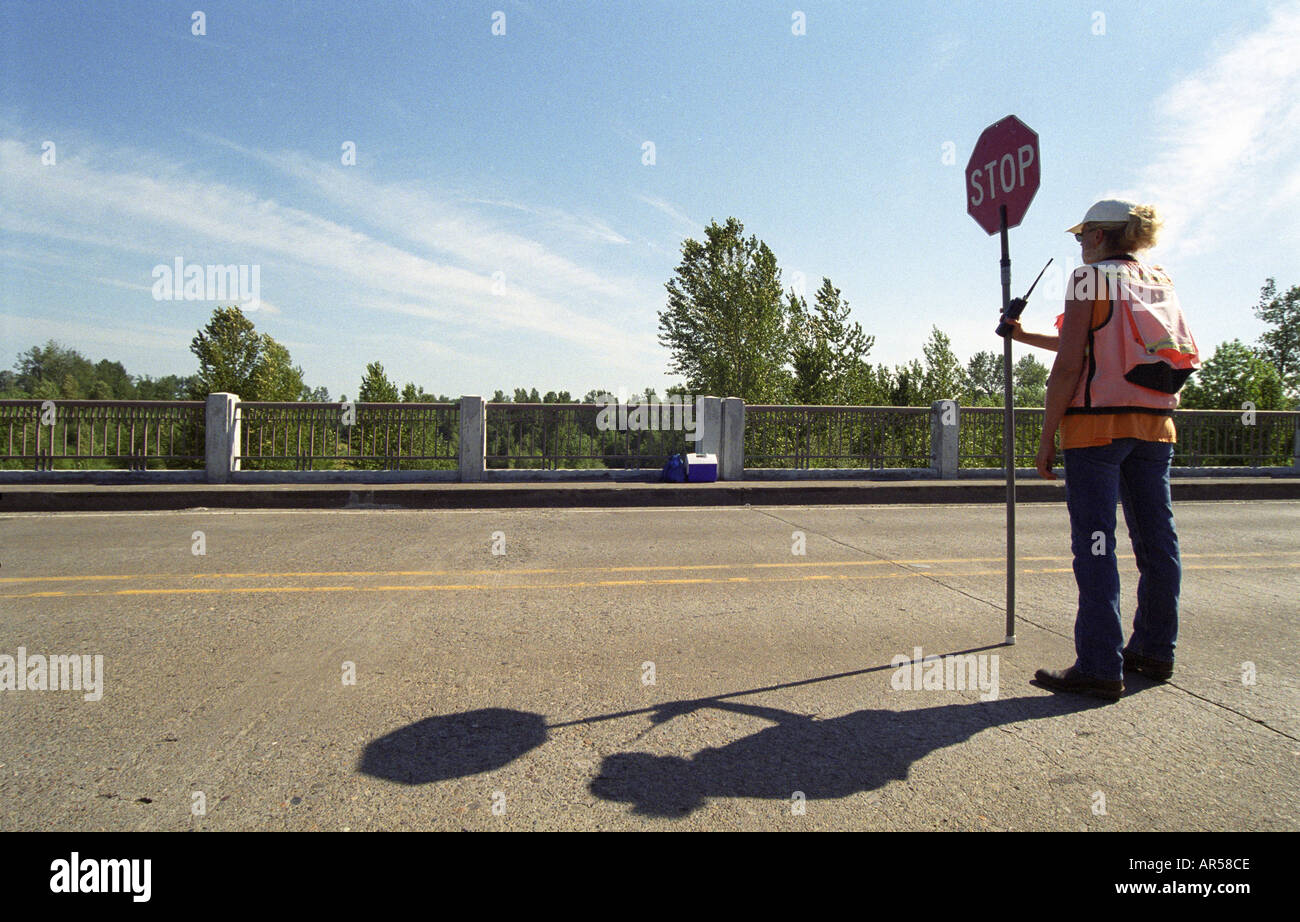Femmina lavoratore su strada tenendo alto il segnale di arresto Foto Stock