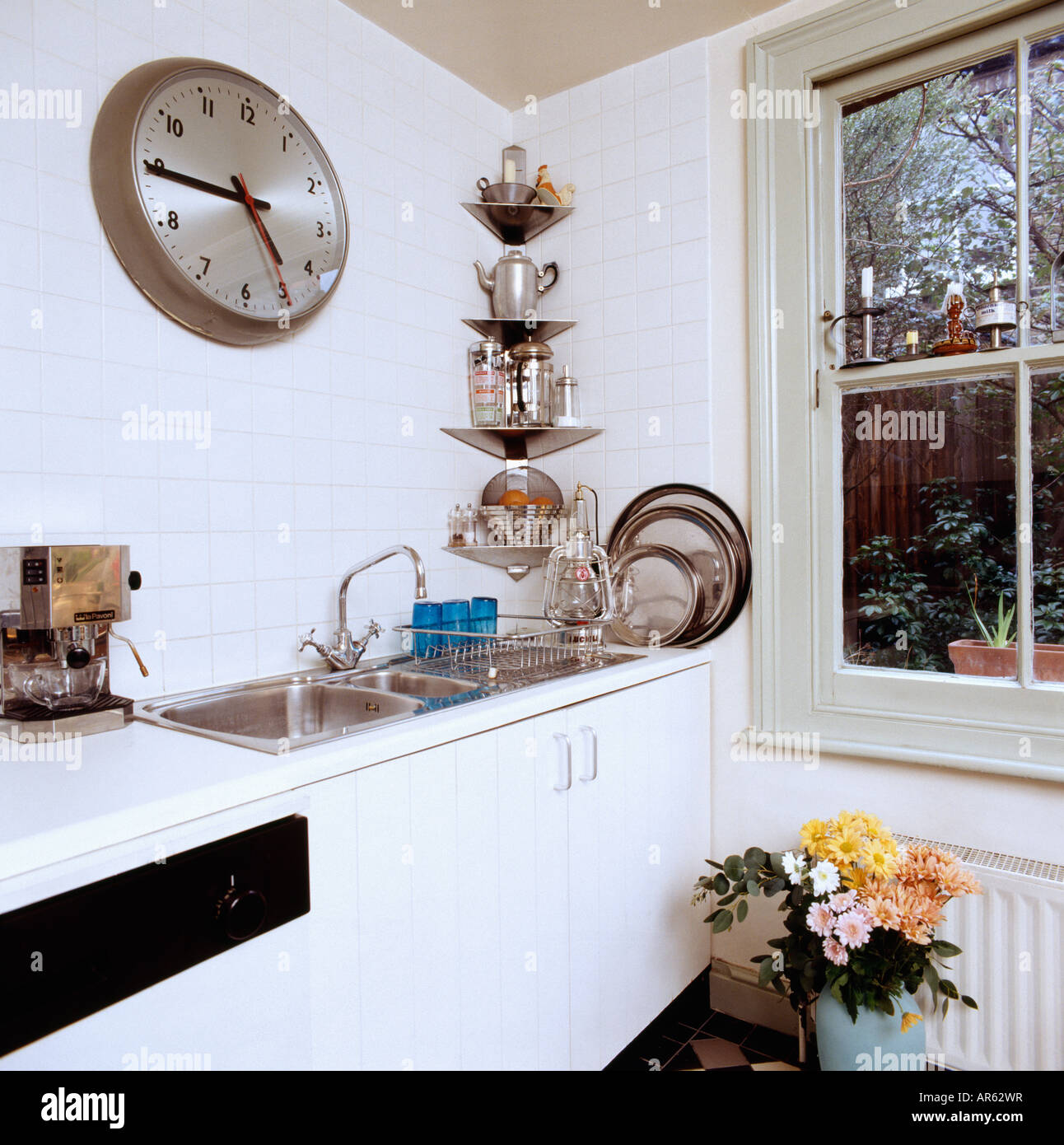 Orologio grande sopra il doppio lavello in acciaio inox in bianco cucina  con angolo acciaio scaffali accanto alla finestra Foto stock - Alamy