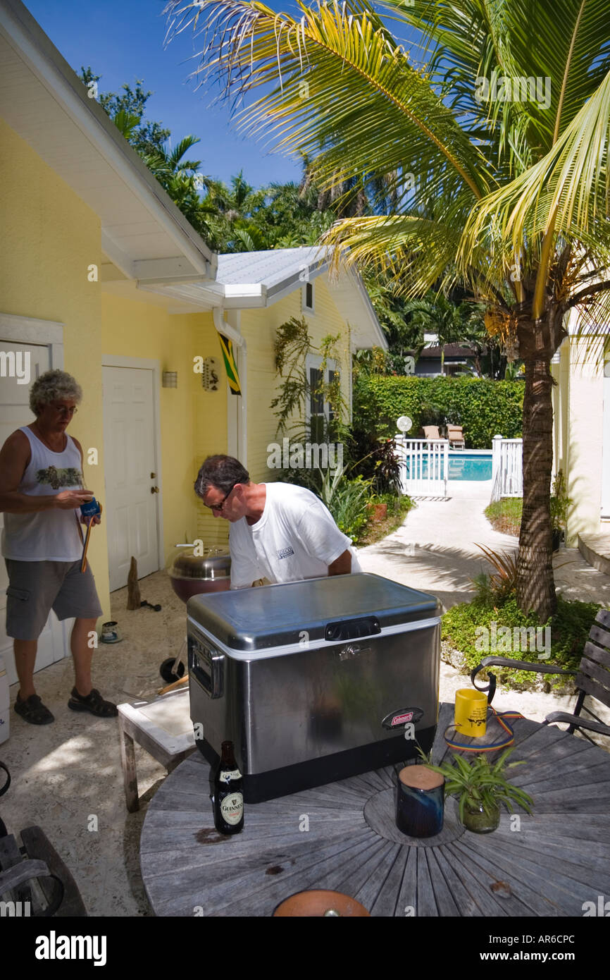 Due uomini di mezza età in piedi al di fuori di una casa nei tropichi preparando per un barbecue Foto Stock