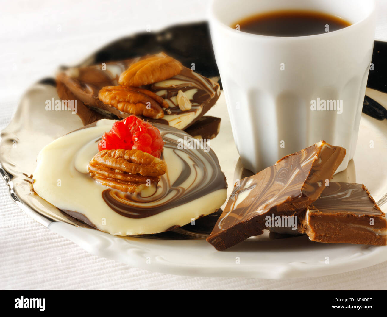 Bianco, di pianura e di cioccolato al latte di turbolenza in marmo con fragole fresche e noci pecan su un vassoio con un caffè nero. Foto Stock