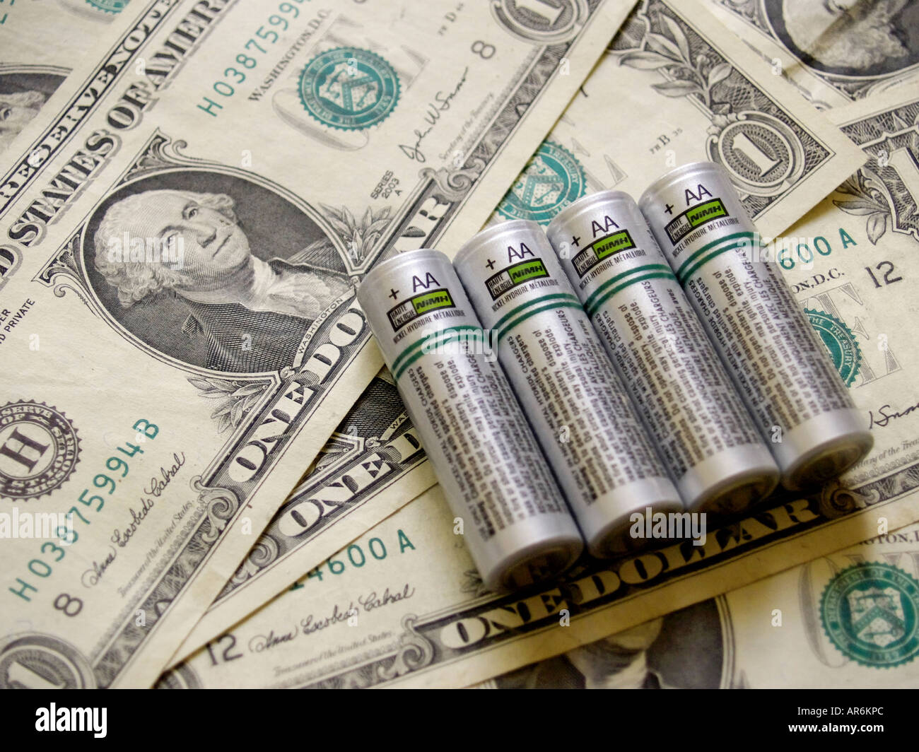 Quattro color argento AA NiMH celle della batteria contro uno sfondo di fatture del dollaro. Foto Stock