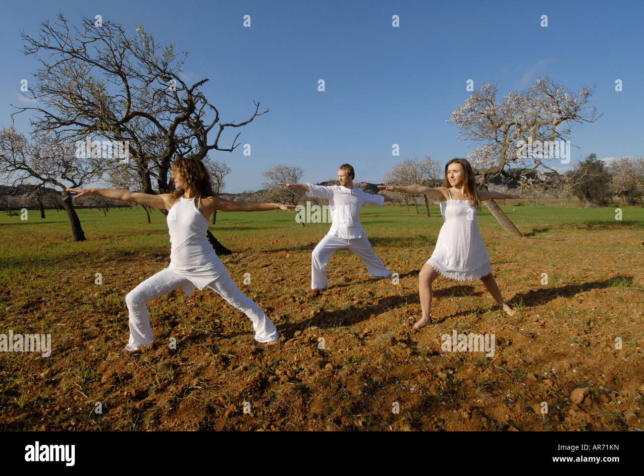 Signor tre persone, uno svedese uomo, una donna brasiliana e una donna spagnola, la pratica dello yoga nei campi di Ibiza, Spagna Foto Stock