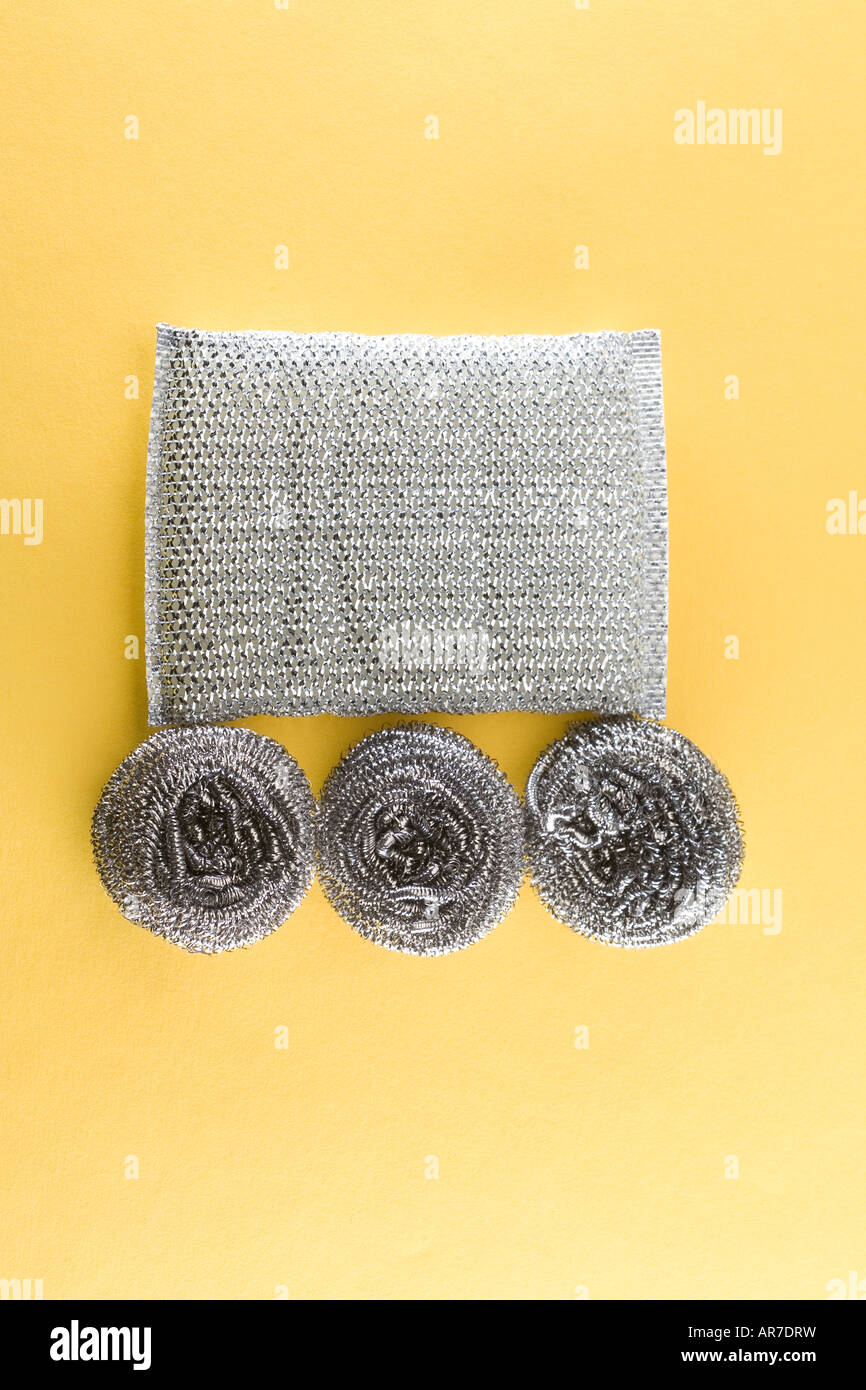 Modello di argento lucide nuovo con lana di acciaio spugne per la pulizia con cerchi e quadrati su sfondo giallo. Foto Stock