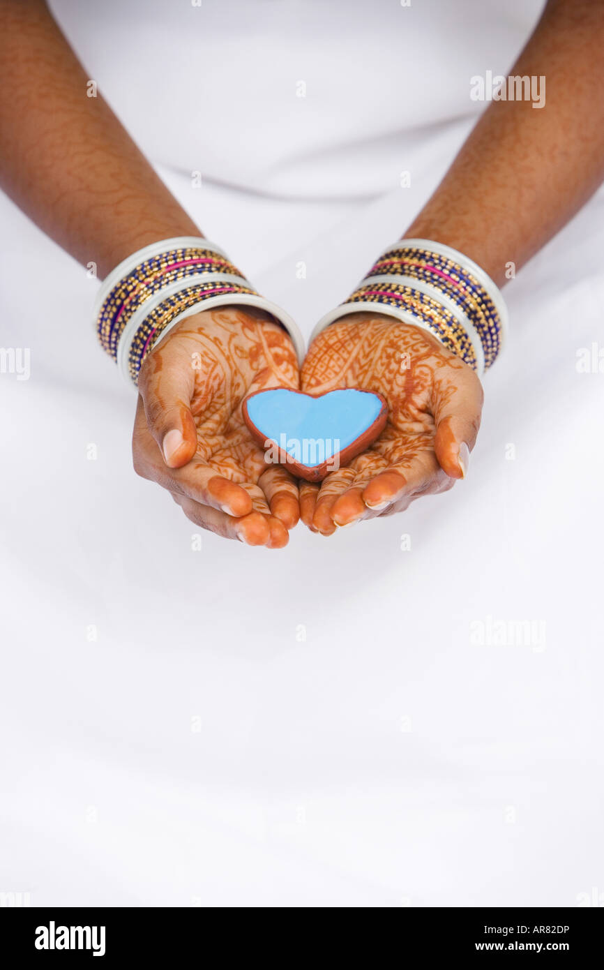 Ragazza indiana con henné mani tenendo a forma di cuore ad un piatto. India Foto Stock