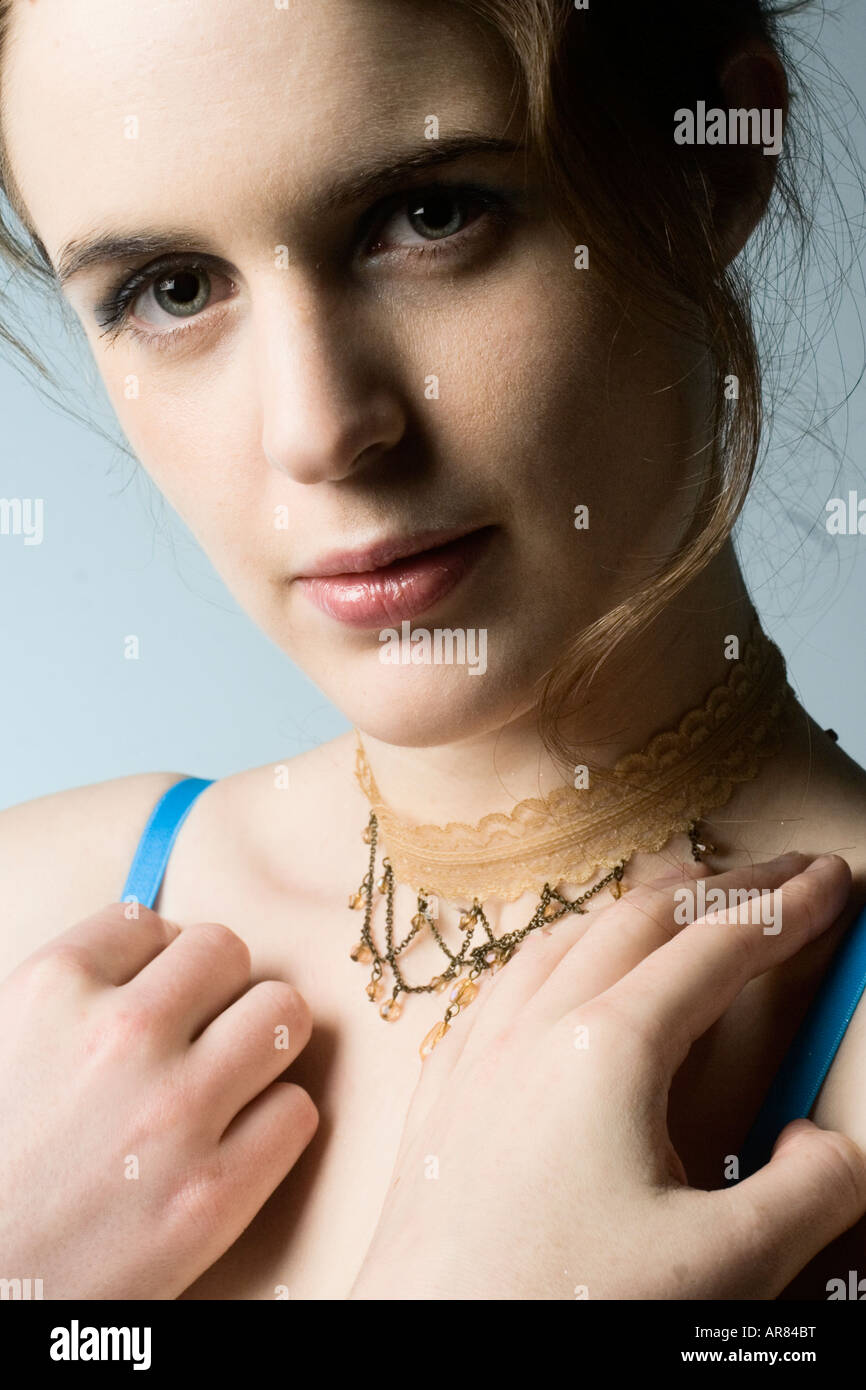 Headshot ritratto di una giovane donna bruna su sfondo azzurro. Foto Stock
