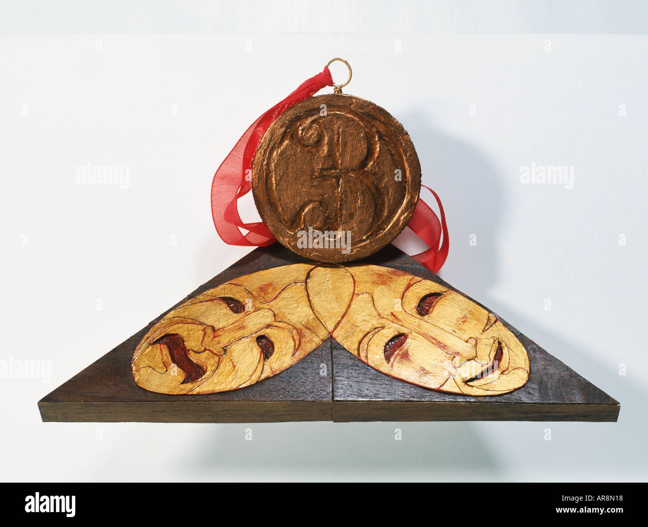 Medaglia di bronzo con grande numero 3 , in appoggio ad un apice di base triangolare raffigurante incastro due maschere teatrali Foto Stock