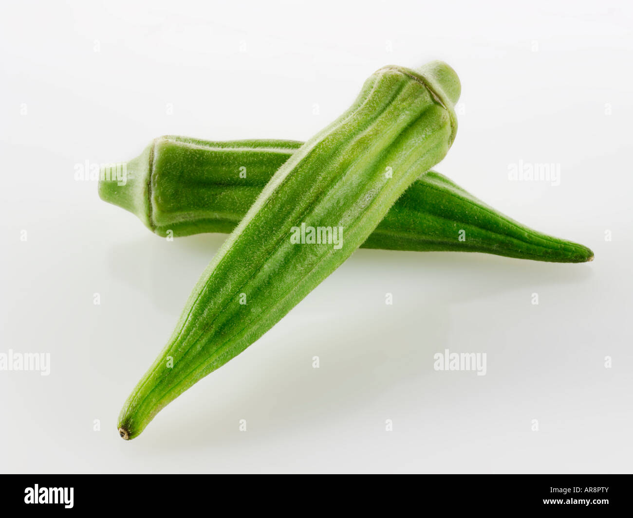 Fresche, Ochra Bhindi o Signore dita intere e non cotti contro uno sfondo bianco per tagliare Foto Stock