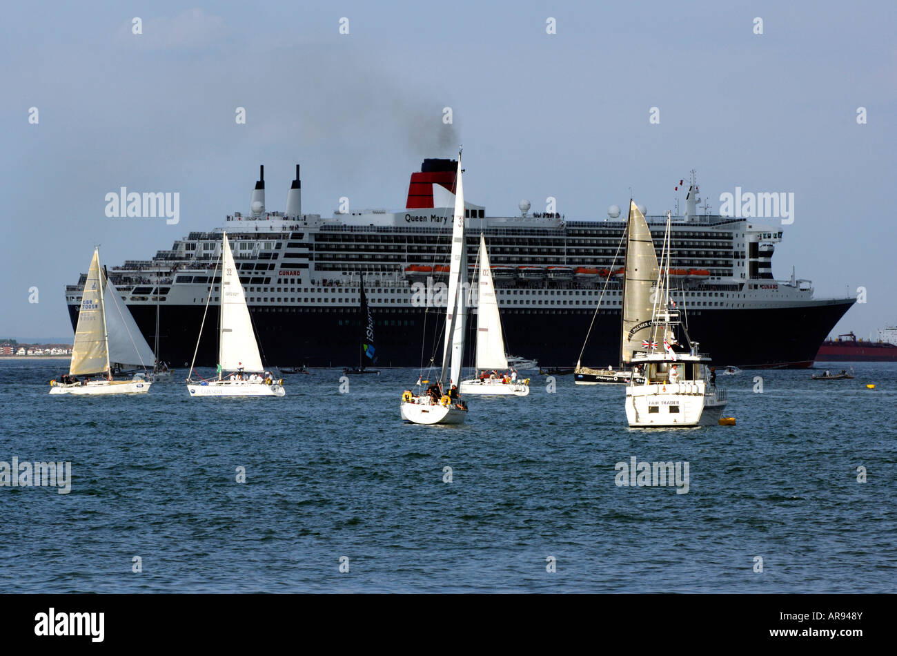 La ocean liner cunard Queen Mary 2 due II nel solent passando un numero di lotto di yachts in primo piano durante la cowes week Foto Stock