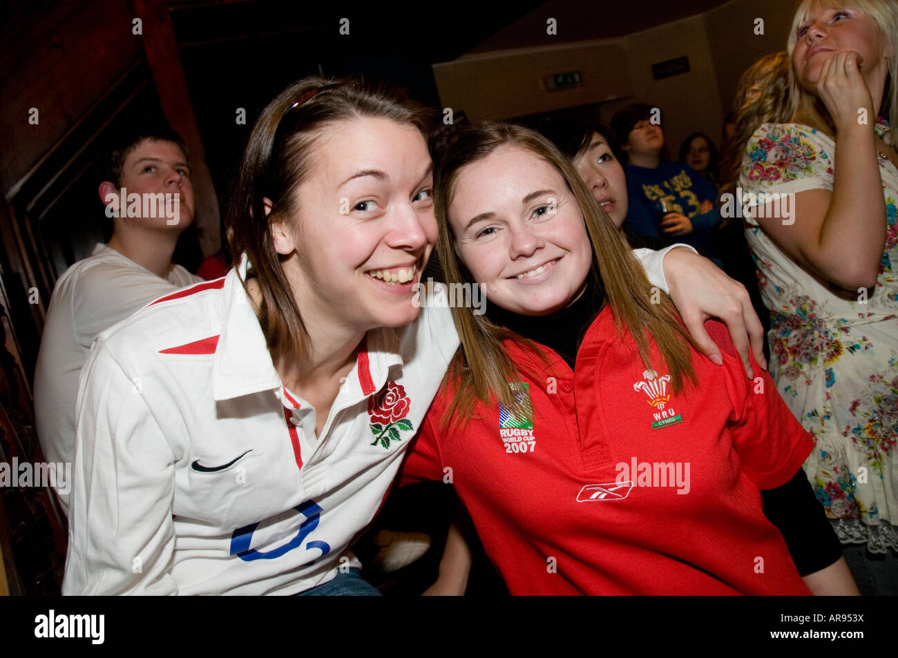 Due giovani donne uno un sostenitore in Inghilterra le altre una ventola del Galles guardare la partita di rugby insieme nel pub - Il Galles vinse 26-19 Foto Stock