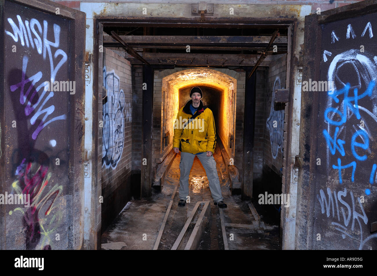 Uomo in piedi nel tunnel di una abbandonata fabbrica di mattoni forno con graffiti su porte Don Valley laterizi Toronto Foto Stock