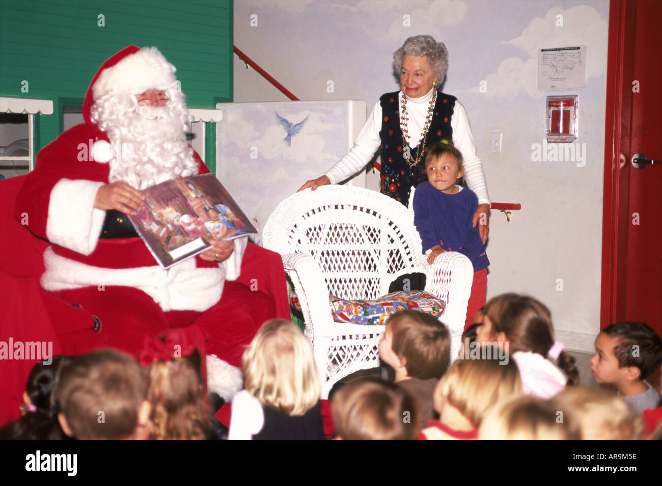 Santa la lettura di storie di Natale al gruppo di bambini delle scuole Foto Stock