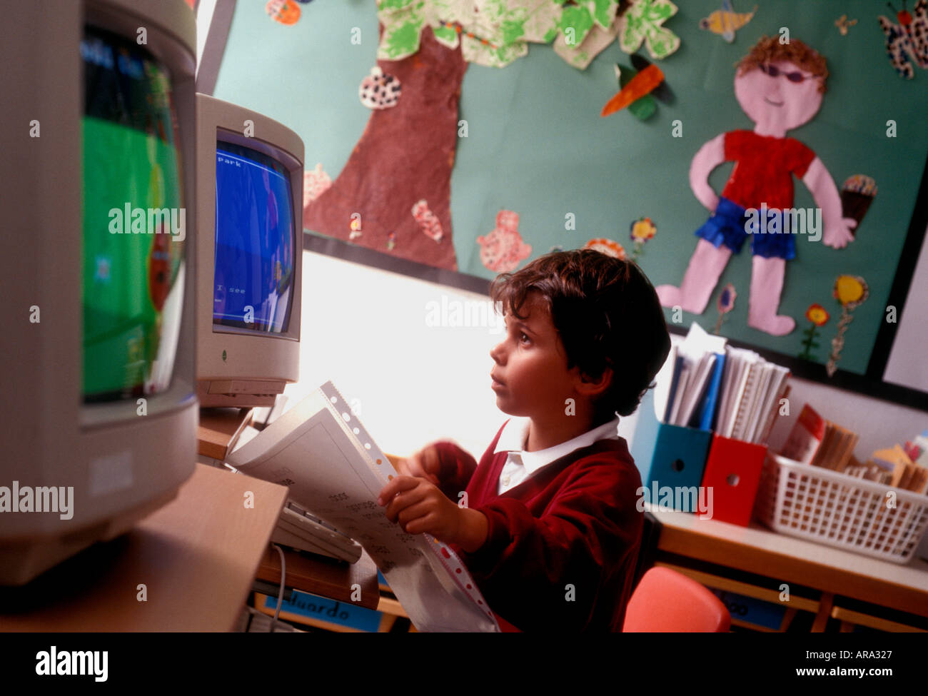 Schermo del computer degli anni '90 ragazzo della scuola infantile di età compresa tra 3 e 5 anni a schermo del computer con opere d'arte in background prime lezioni di computer infantile negli anni '90 Foto Stock