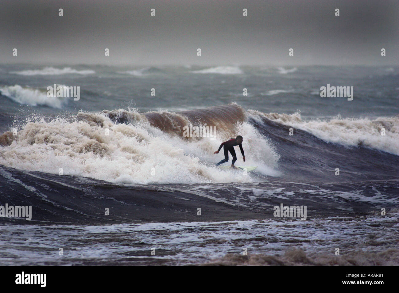 Un surfista rende il meglio del mare in tempesta a Exmouth South Devon Regno Unito Foto Stock