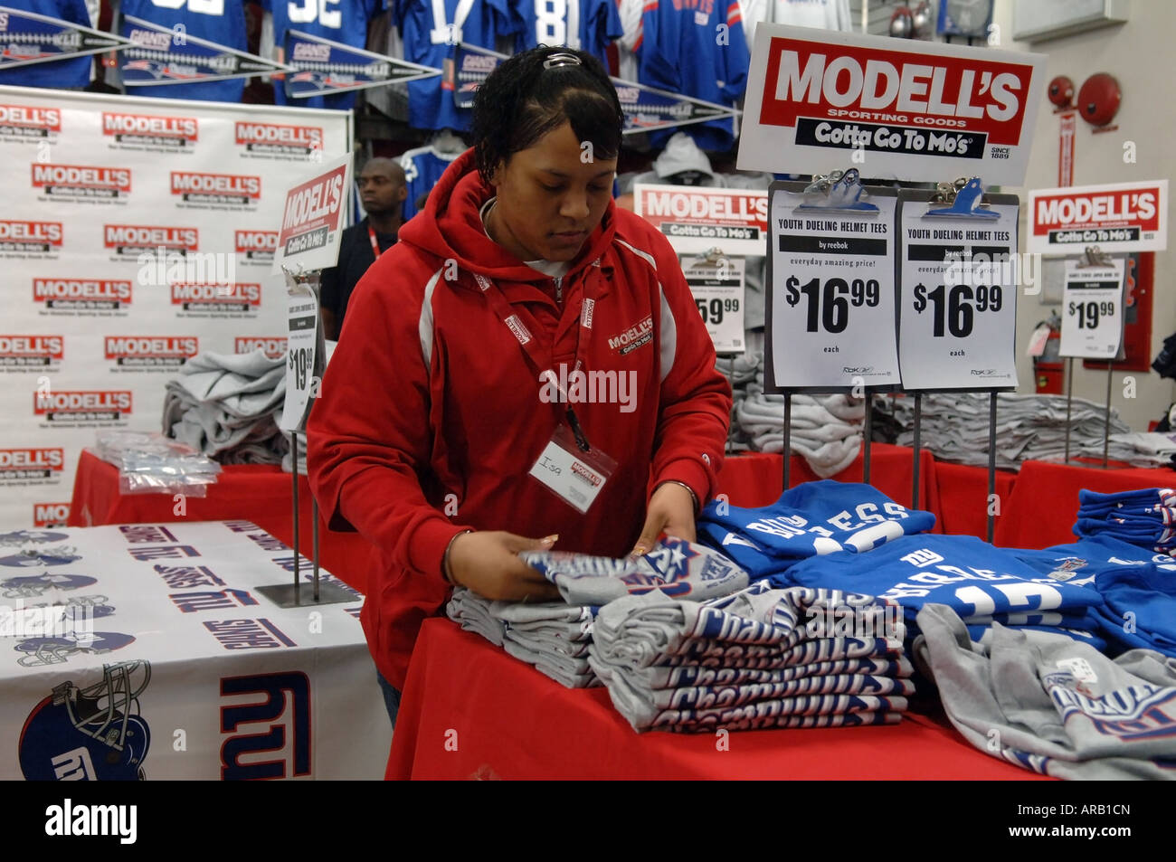Addetto al Modell s negozio di articoli sportivi a NYC organizza merchandise Foto Stock