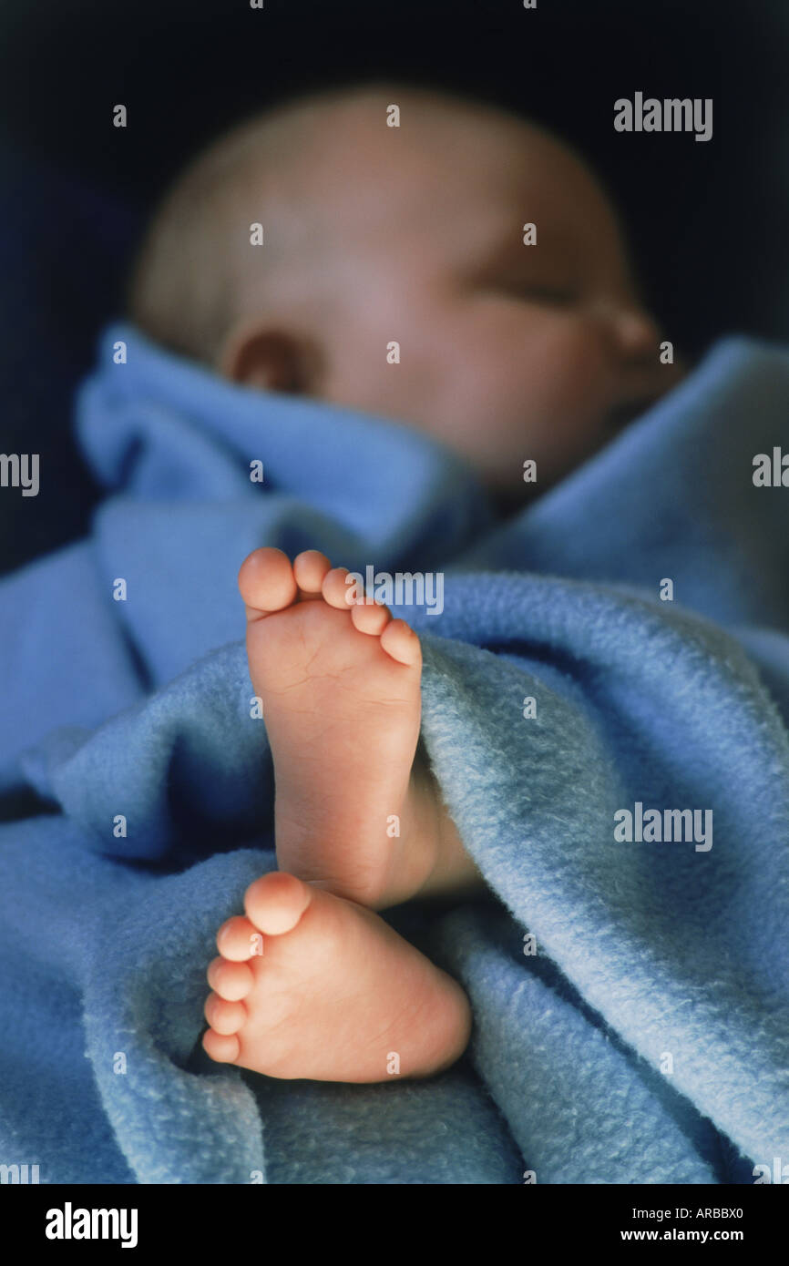 Piedi del bambino di dormire 3-6 mese vecchio spiata da sotto la coperta blu Foto Stock