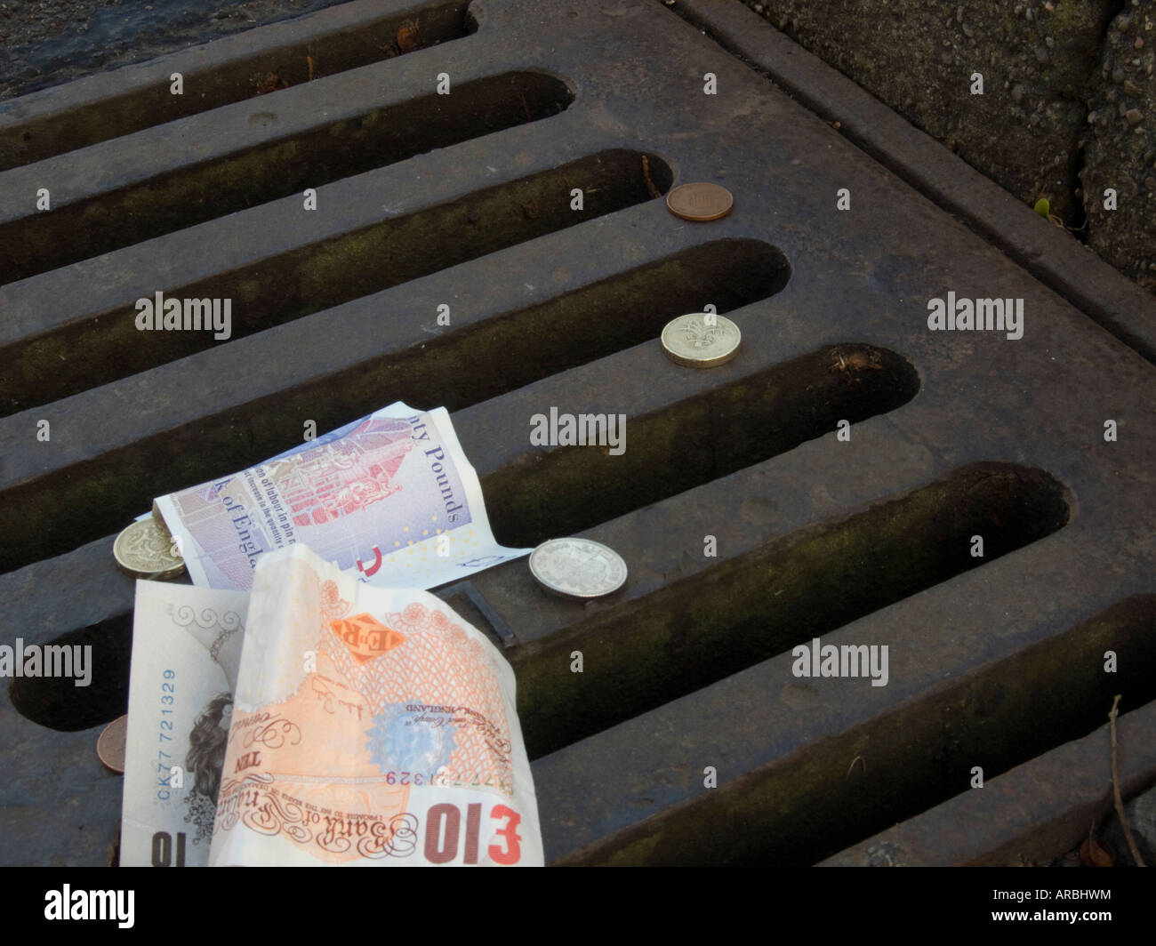 Immagine concettuale delle banconote e delle monete metalliche in euro su una strada di scarico laterale Foto Stock