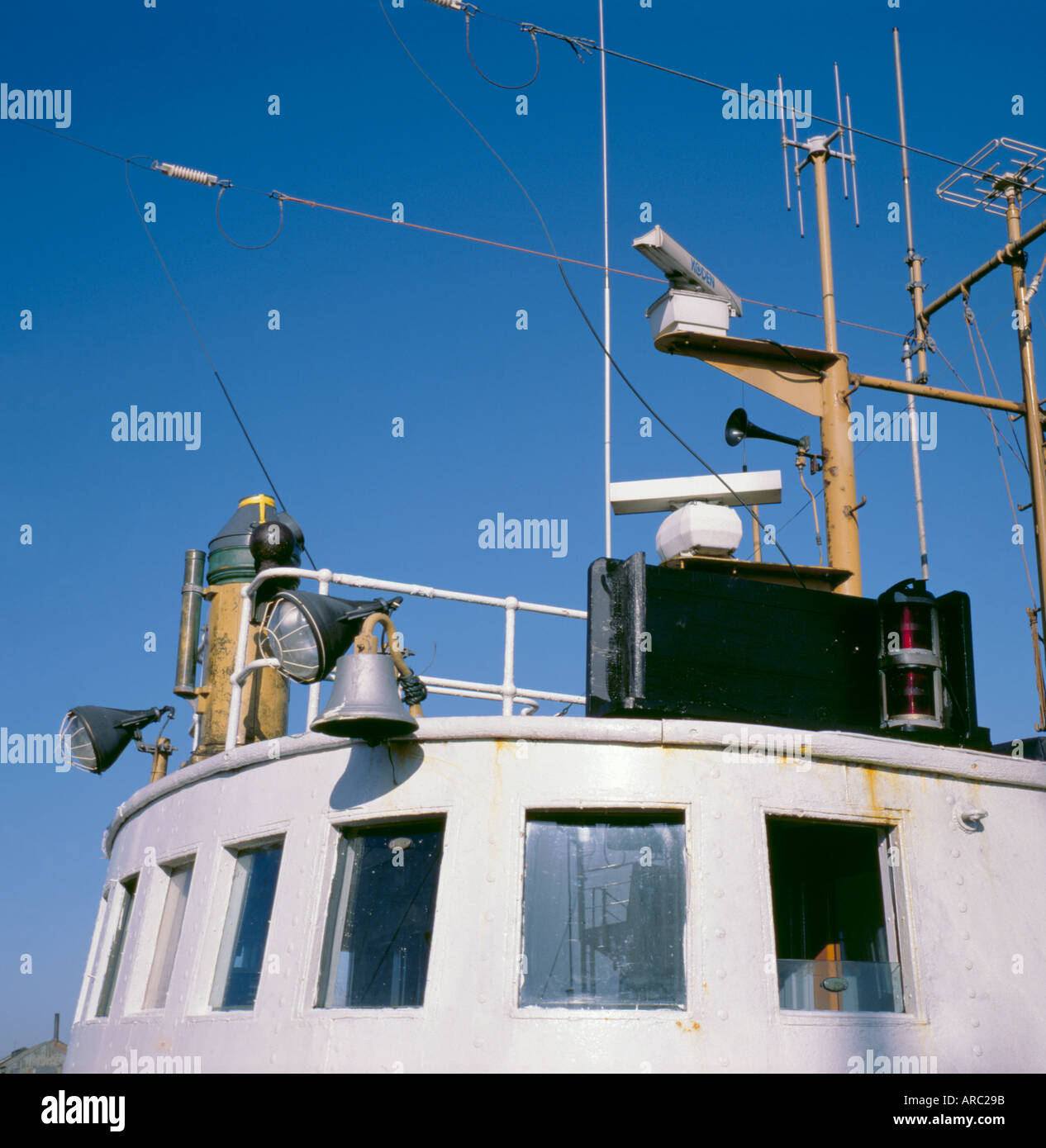 Dettaglio del tetto della cabina della sovrastruttura di una barca da pesca che mostra le luci di ricerca, navi campana, antenna radio e antenne, Foto Stock