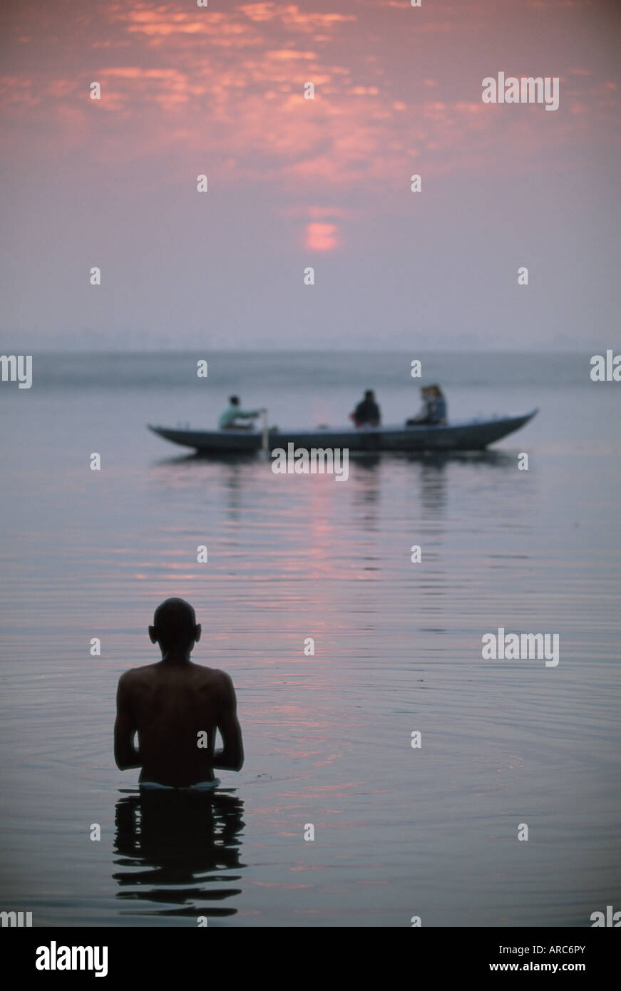 Barca passando un uomo in piedi nel fiume santo , Fiume Gange (ganga), Varanasi (Benares), nello stato di Uttar Pradesh, India, Asia Foto Stock