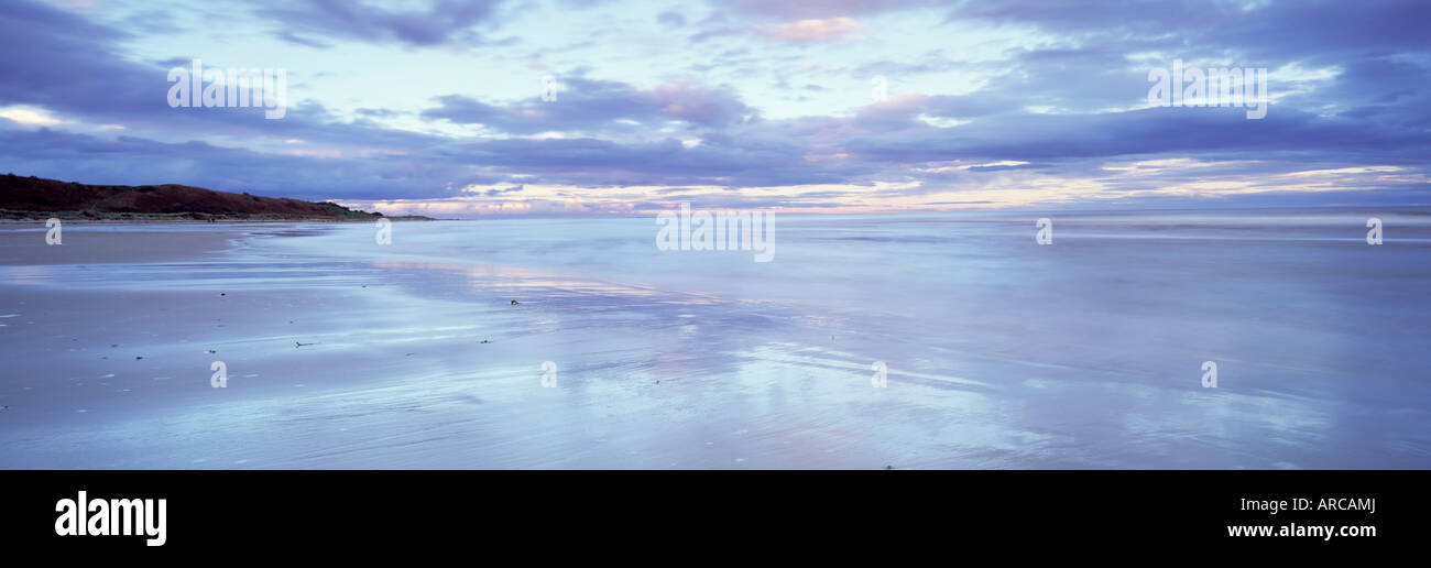 Spiaggia di Alnmouth al tramonto con nuvole drammatico riflettendo in sabbia bagnata con la bassa marea, nelle vicinanze Alnwick, Northumberland, England, Regno Unito Foto Stock