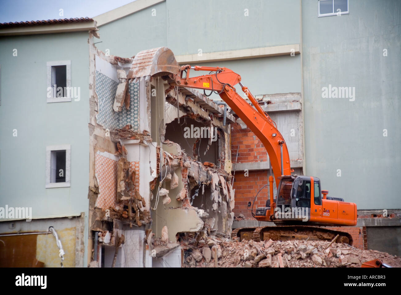 Un retroescavatore è usato per demolire un cemento armato edificio a Fatima in Portogallo Foto Stock