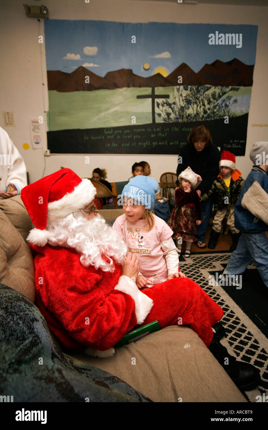 Una Santa Claus svolge volontariato locale con i bambini durante le attività di Natale per le persone a basso reddito e i senzatetto locali in Barstow CA Foto Stock