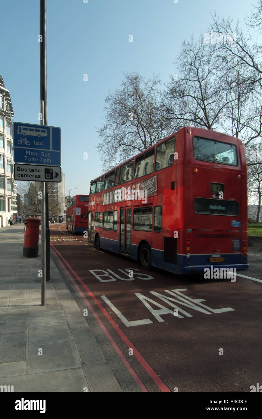 London Park Lane 2 bus che viaggiano a velocità in ampia corsia degli autobus passando fermata bus tutti segnato in rosso asfalto Foto Stock
