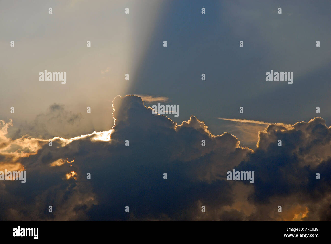 Serata sole che splende da dietro il banco di nuvole e raggi sporgenti oltre il cielo Foto Stock