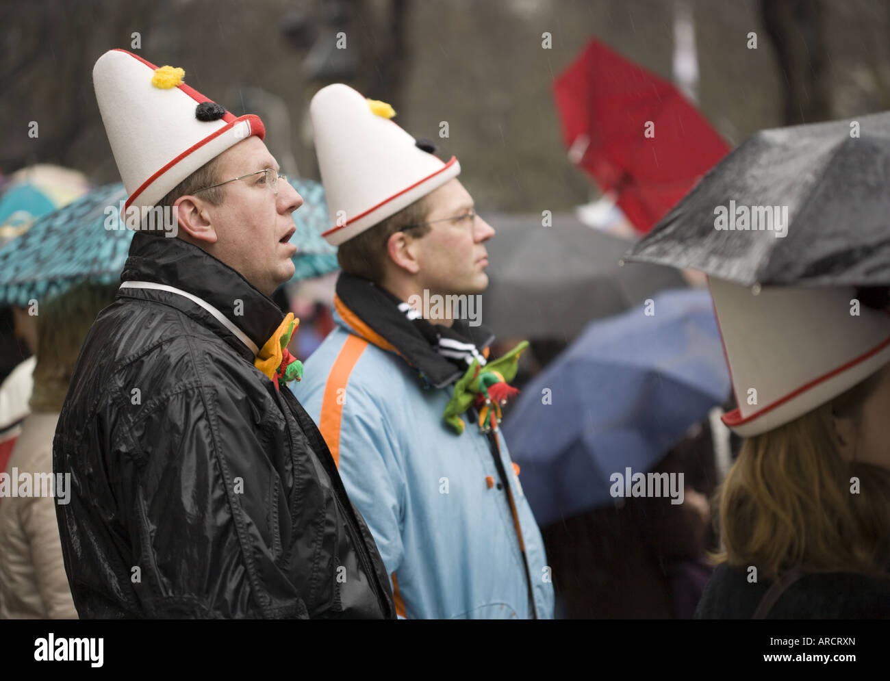 Molte persone con clown cappelli, abbigliamento pioggia, ombrelli, guardando il Rosenmontagszug a Düsseldorf Foto Stock