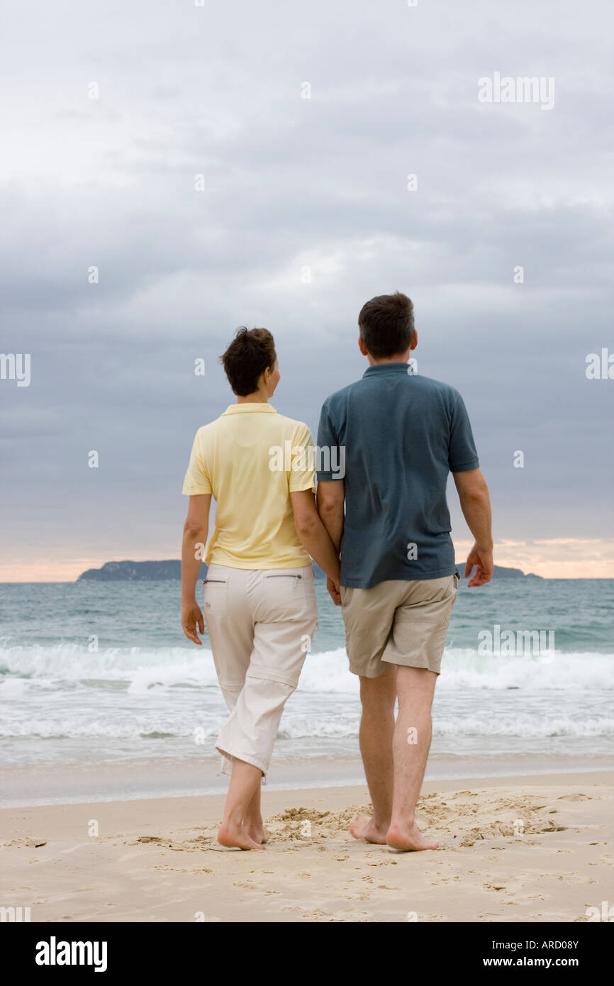 Giovane camminando mano nella mano sulla spiaggia Foto Stock