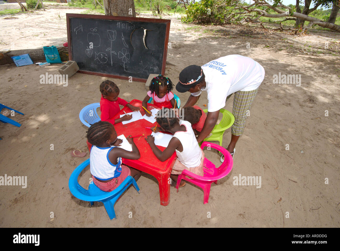 Insegnanti volontari educare una classe di bambini mozambicani in una boccola classe. Foto Stock
