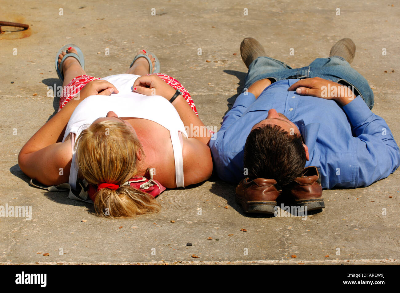 Una completamente vestito giovane posa in sun one utilizzando scarpe come un cuscino per la testa di riposo su Foto Stock