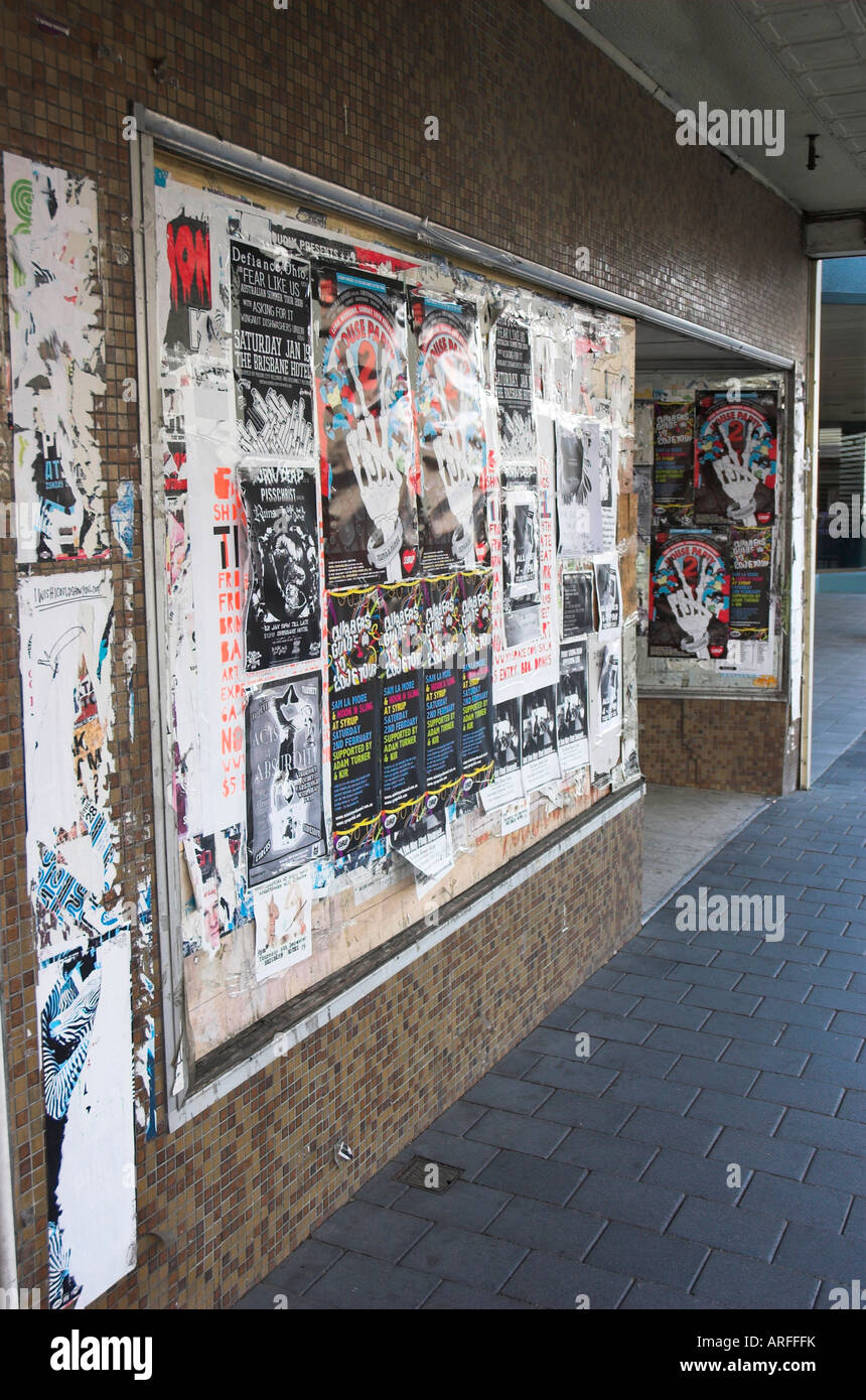 Saliti a bordo un negozio in una strada di città ricoperta di poster per eventi Foto Stock