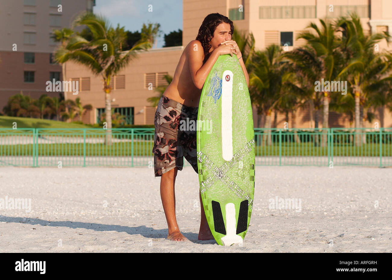 Un ragazzo adolescente guardando le onde ottenere pronto a guidare il suo skim board Foto Stock