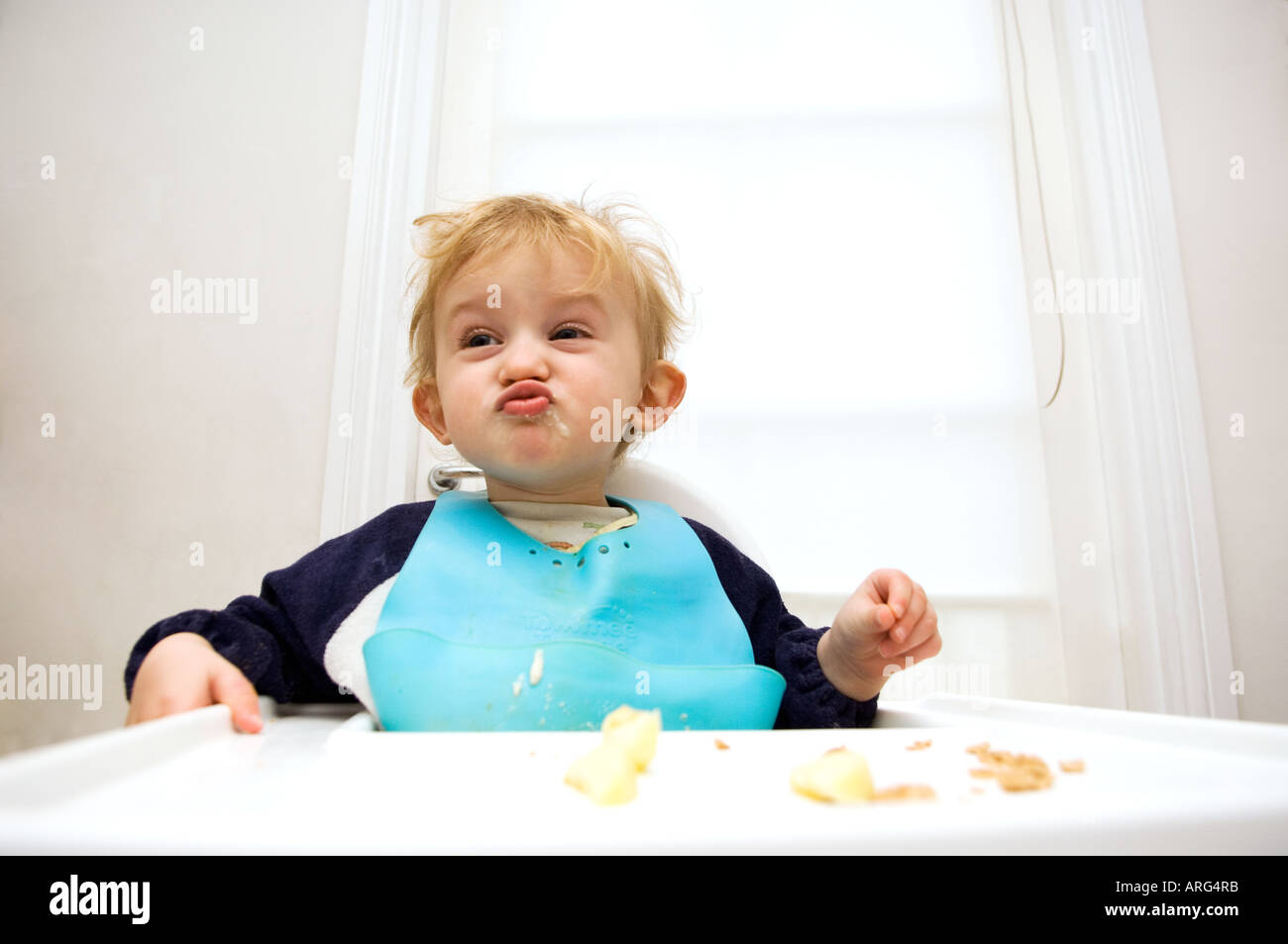 Baby boy in alta sedia tirando la faccia Foto Stock