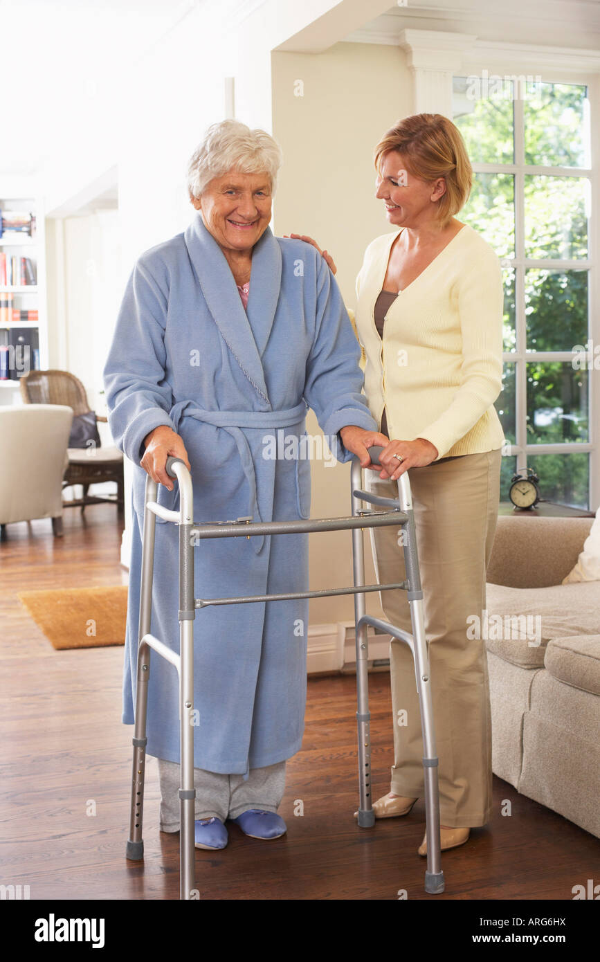 Senior donna ricevere assistenza con utilizzando Walker Foto Stock