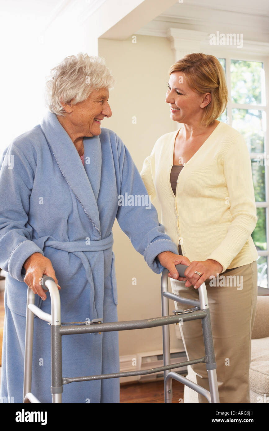 Senior donna ricevere assistenza con utilizzando Walker Foto Stock